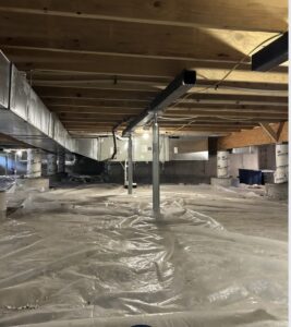 A crawl space with a plastic vapor barrier on the floor, exposed wooden floor joists above, metal support beams, and ductwork running across the ceiling.
