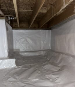 A crawl space with exposed wooden beams and a floor and walls covered in white plastic sheeting for moisture protection.